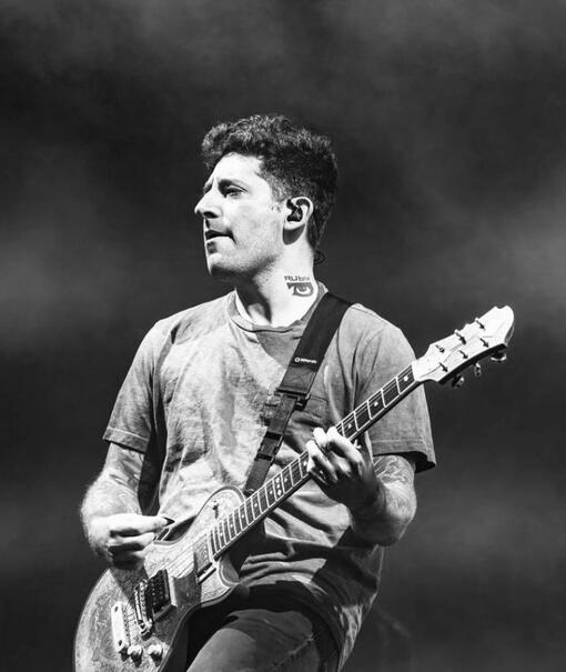 This is a photo of Joe Trohman playing electric guitar and looking off to the left of the image.