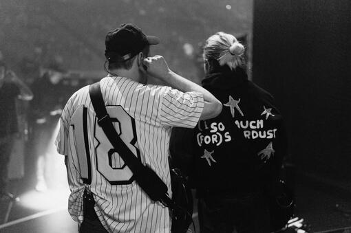 This is a photo of Patrick Stump with his elbow on Pete Wentz's shoulder, both seen from the back.